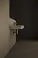 Waschtisch mit integrierter Armatur, montiert an einer Wand in einem modernen Raum. Die Oberfläche ist geschliffen und in einem neutralen Farbton gehalten. Ideal Standard.